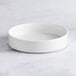 An Acopa Lore bright white porcelain deep plate on a table.