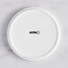 A white Acopa Lore porcelain plate with raised rim and black text.