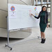 A woman in a green dress pointing at a Luxor whiteboard on a mobile stand.