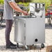 A person washing hands in a stainless steel sink on a portable hand sink cart.