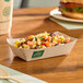 A rectangular compostable bamboo food tray filled with a mixed bean and corn salad.