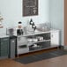 A kitchen with a Regency stainless steel beverage table on a counter with a coffee pot and cups.