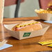 A rectangular compostable bamboo food tray holding a hot dog with mustard.