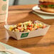 A rectangular compostable bamboo food tray filled with a mixed bean and corn salad.