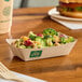 A rectangular compostable bamboo food tray filled with a broccoli salad.