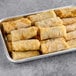 A tray of Cuisine Innovations vegetable spring rolls on a gray surface.