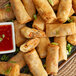 A plate of fried Cuisine Innovations Vegetable Spring Rolls with dipping sauce.