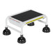 A white step stool with black rubber feet.
