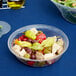 A Carlisle pebbled serving bowl filled with salad on a blue table.