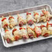 A tray of Cuisine Innovations antipasto skewers with meat and vegetables on a gray surface.