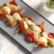 A plate of Cuisine Innovations antipasto skewers with vegetables and herbs.