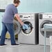 A man standing next to a Crossover front load commercial washer.