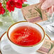 A hand holding a Florida Crystals Turbinado Cane Sugar packet over a cup of tea.