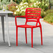 A red Lancaster Table & Seating Sol Buoy resin arm chair on a patio.