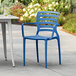 A blue Lancaster Table & Seating Sol resin arm chair sits on a white table outside.