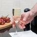 A hand holding a Stolzle Weinland flute of wine over a table with grapes