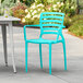 A blue Lancaster Table & Seating resin arm chair on a patio.