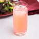 A Stolzle Weinland tall tumbler filled with pink liquid and ice on a table