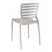 A white plastic Lancaster Table & Seating side chair with a slatted back.