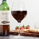 A Stolzle Exquisit burgundy wine glass filled with red wine on a table.
