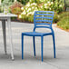 A blue Lancaster Table & Seating Sol resin chair on an outdoor patio.