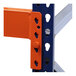 A close-up of a metal Interlake Mecalux pallet rack beam with orange and blue bolts.