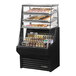 A True refrigerated air curtain merchandiser with dry bakery display shelves holding pastries.