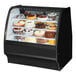A True black refrigerated bakery display case with cakes inside.