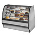 A True refrigerated bakery display case with cakes on it.