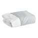A folded 1888 Mills grey bed skirt with white and grey sheets.