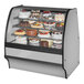 A True refrigerated bakery display case with cakes on it.