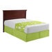 A king size bed with green and white sheets and a green bed skirt.