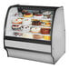 A True refrigerated bakery display case with cakes on it with a white interior.