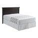 A bed with a 1888 Mills Beyond Impressions gray circles top sheet on a bed with a white sheet and black headboard.