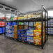 A Wanzl beer shelving unit with shelves filled with boxes and bottles of beer.