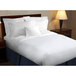 A bed with a 1888 Mills white top sheet and pillows.