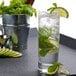 A Stolzle New York Collins Glass filled with water, limes, and mint leaves.