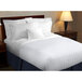 A bed with white 1888 Mills Beyond Woven satin stripe top sheets and pillows.