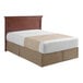 A bed with a beige striped 1888 Mills Beyond Impressions top sheet on a wood headboard.