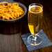 A Stolzle stemmed beer glass filled with beer next to a bowl of pretzels.