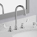 An American Standard deck-mount faucet with a gooseneck spout and wrist blade handles on a bathroom sink.