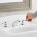 A hand pressing the American Standard Monterrey deck-mount faucet on a counter.