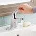 A hand holding the American Standard Colony Pro single lever faucet with water running.