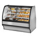 A True curved glass dual zone bakery display case filled with various pastries.