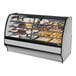 A True dual zone bakery display case with a curved glass front and stainless steel interior full of baked goods.