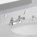 A close-up of an American Standard deck-mount lavatory faucet with wrist blade handles.