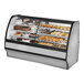 A True refrigerated dual zone bakery display case with a curved glass front and white interior holding various types of pastries.