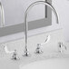 An American Standard deck-mount faucet with two spouts on a white surface.