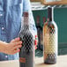 A hand holding a bottle of wine with a Franmara bottle protector sleeve.