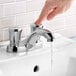 A close-up of a hand pressing an American Standard metering faucet